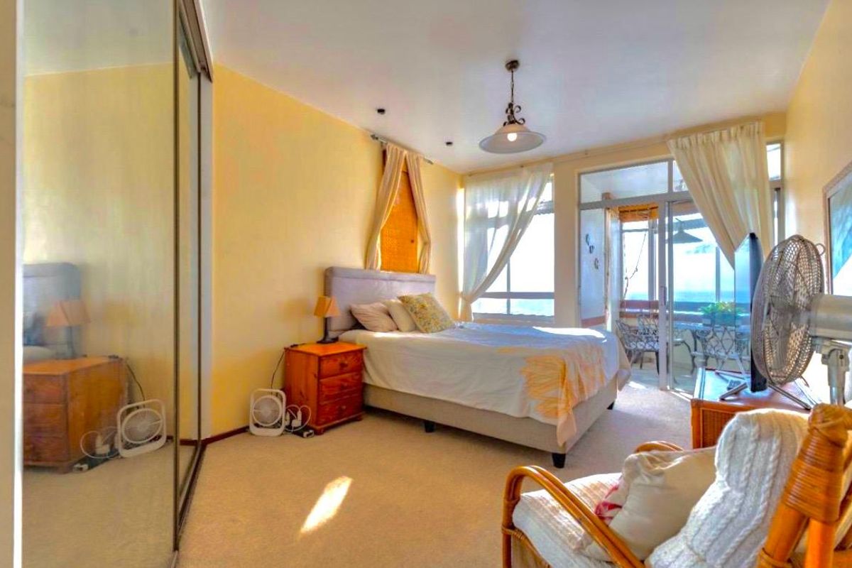A bedroom featuring carpet flooring, a built-in mirrored wardrobe, and direct access to an adjoining balcony through sliding glass doors.