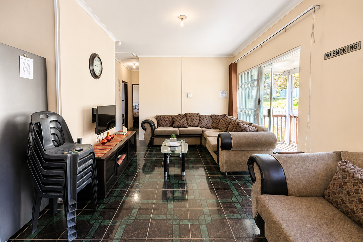 A living room featuring dark patterned floor tiles, neutral walls, and a sliding glass door providing access to an outdoor patio area.