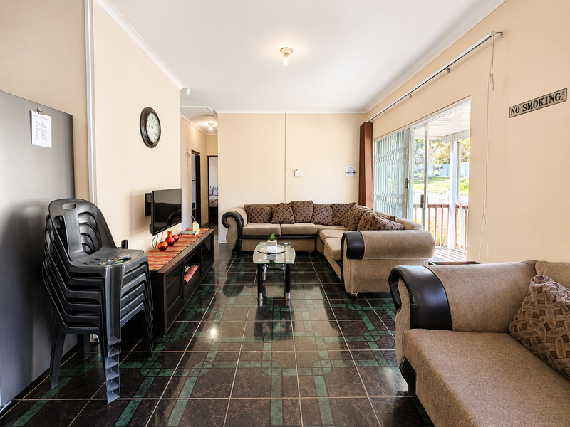 A living room featuring dark patterned floor tiles, neutral walls, and a sliding glass door providing access to an outdoor patio area.