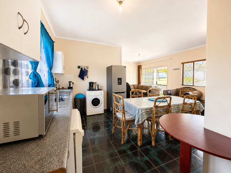Open-plan kitchen and dining area featuring tiled flooring, laminate countertops, and direct access to the outdoor patio through a sliding glass door.
