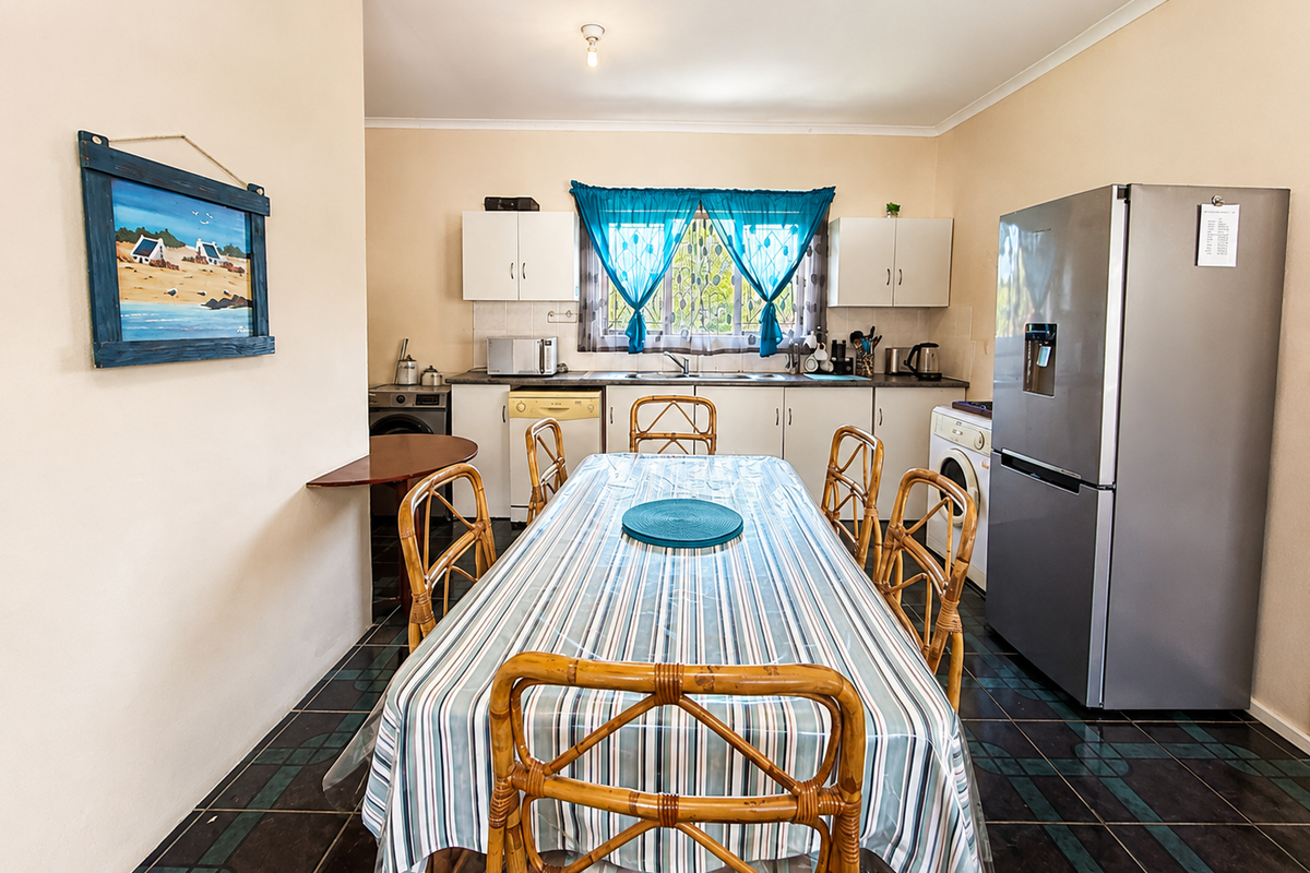 A functional kitchen featuring built-in cabinetry, laminate countertops, a stainless steel sink, and tiled flooring, integrated with a dining area.