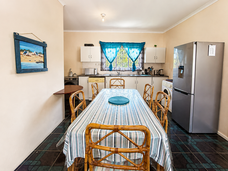 A functional kitchen featuring built-in cabinetry, laminate countertops, a stainless steel sink, and tiled flooring, integrated with a dining area.