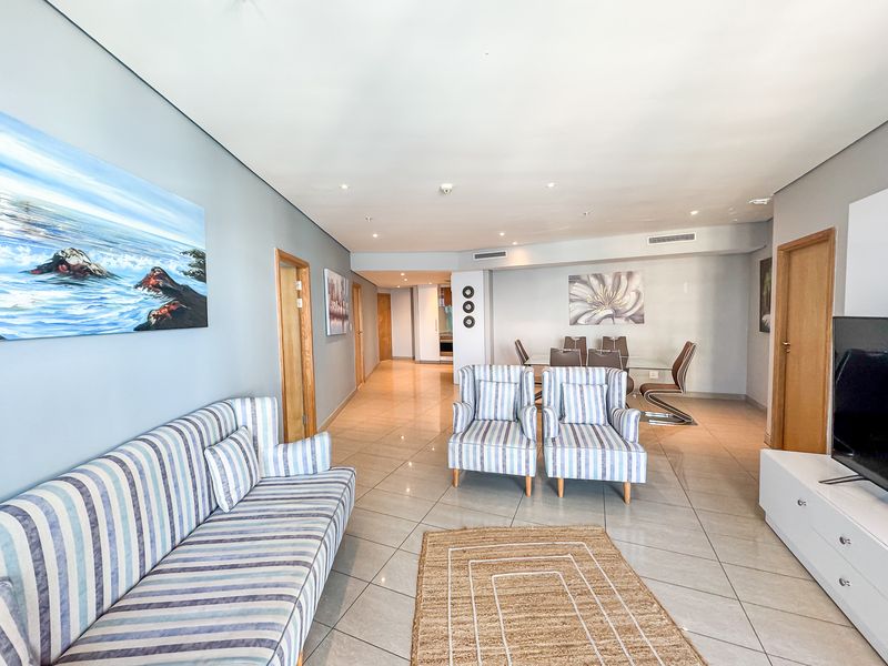 Spacious open-plan living and dining area featuring neutral porcelain floor tiles, recessed lighting, and ducted air conditioning throughout.