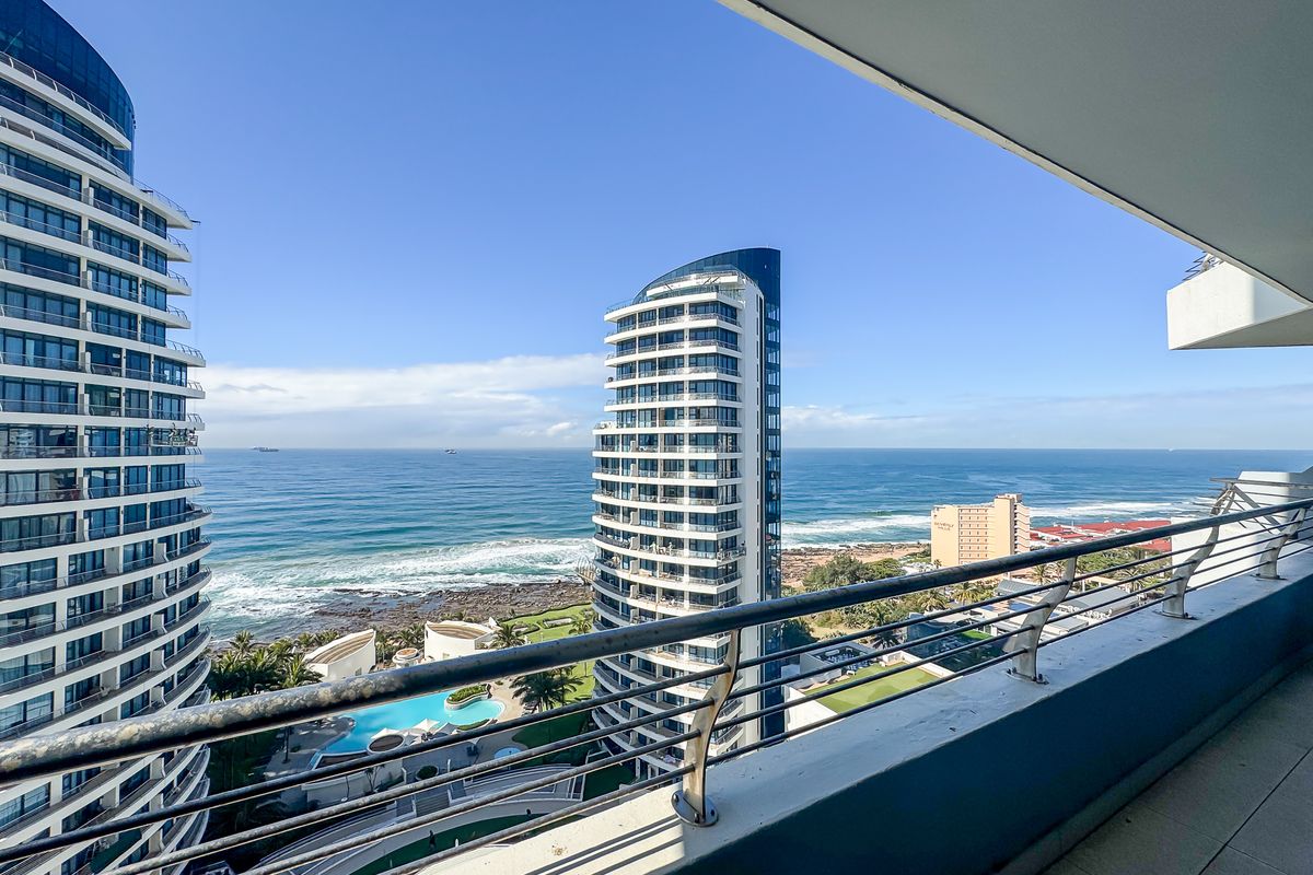 Spacious balcony featuring a modern stainless steel balustrade and tiled flooring, offering expansive ocean and coastal views.