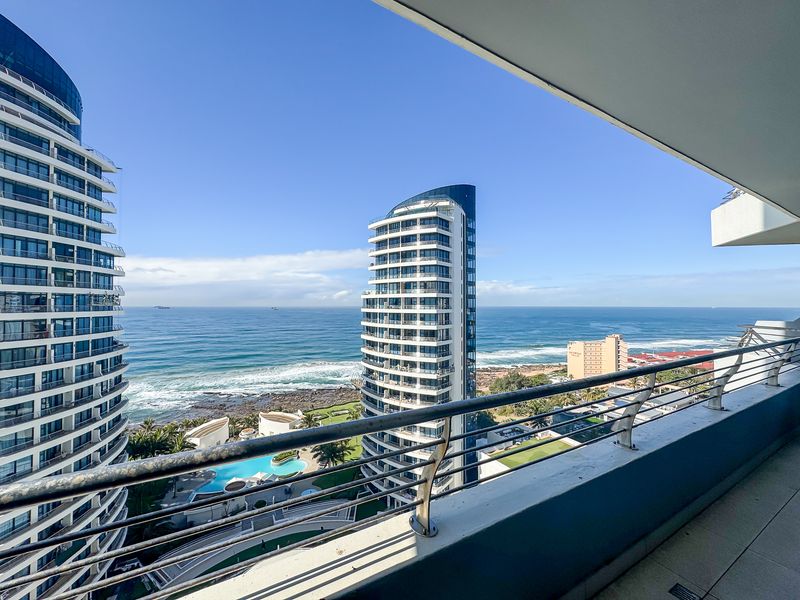 Spacious balcony featuring a modern stainless steel balustrade and tiled flooring, offering expansive ocean and coastal views.
