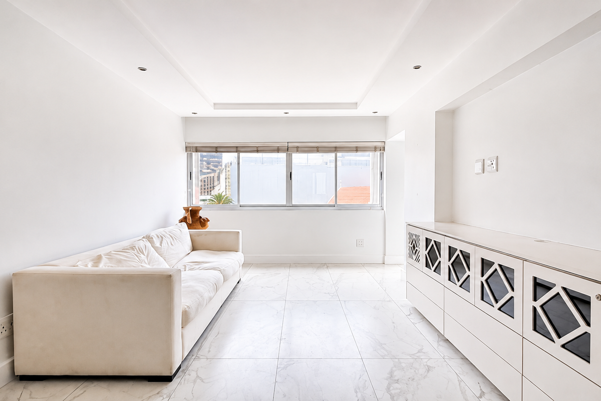 Bright and spacious living area featuring modern marble-look floor tiles, recessed ceiling lighting, and custom built-in cabinetry with decorative fretwork detailing.