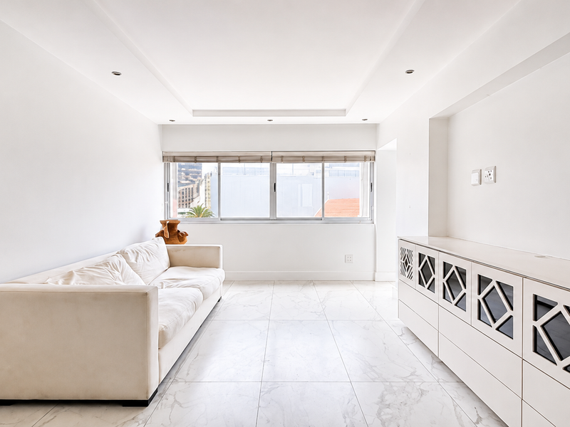Bright and spacious living area featuring modern marble-look floor tiles, recessed ceiling lighting, and custom built-in cabinetry with decorative fretwork detailing.