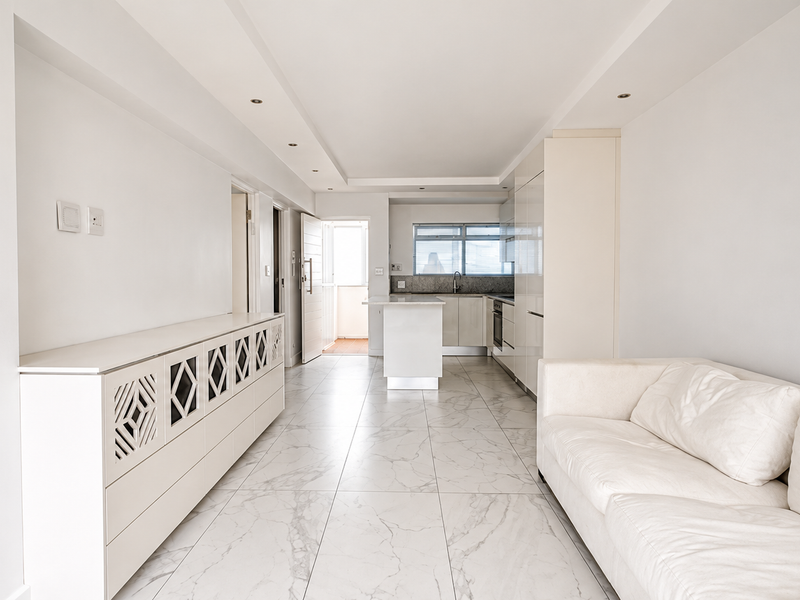 Modern open-plan living and kitchen area featuring sleek white cabinetry, marble-look tiled flooring, and recessed lighting, creating a bright and cohesive living space.