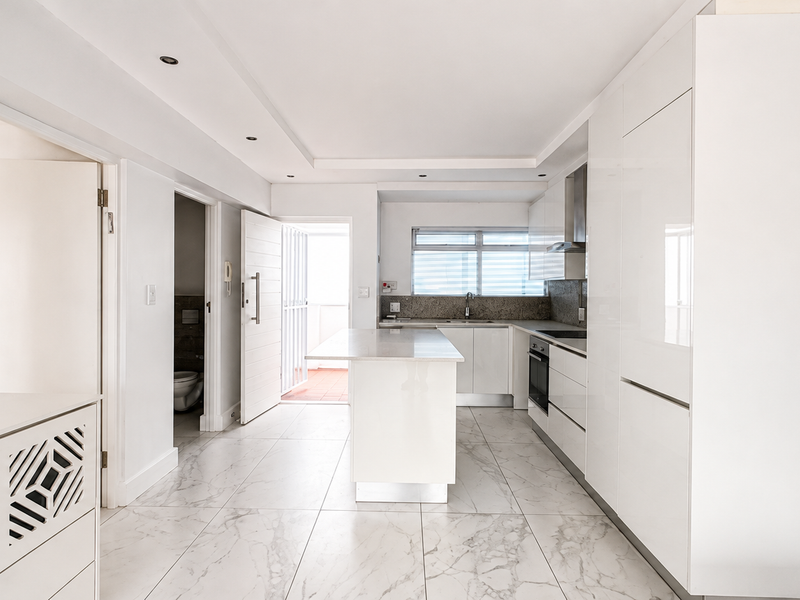 Modern, bright kitchen featuring a central island, integrated cabinetry, stone countertops, and high-quality marble-look floor tiles in an open-plan layout.