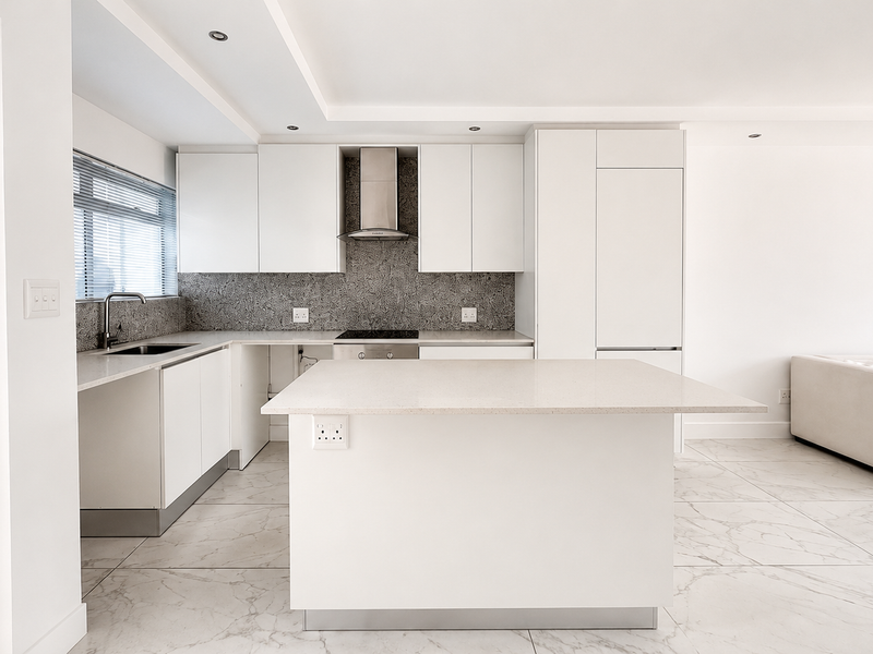 Modern open-plan kitchen featuring white cabinetry, quartz countertops, a central island, and marble-look floor tiles, seamlessly flowing into the living area.