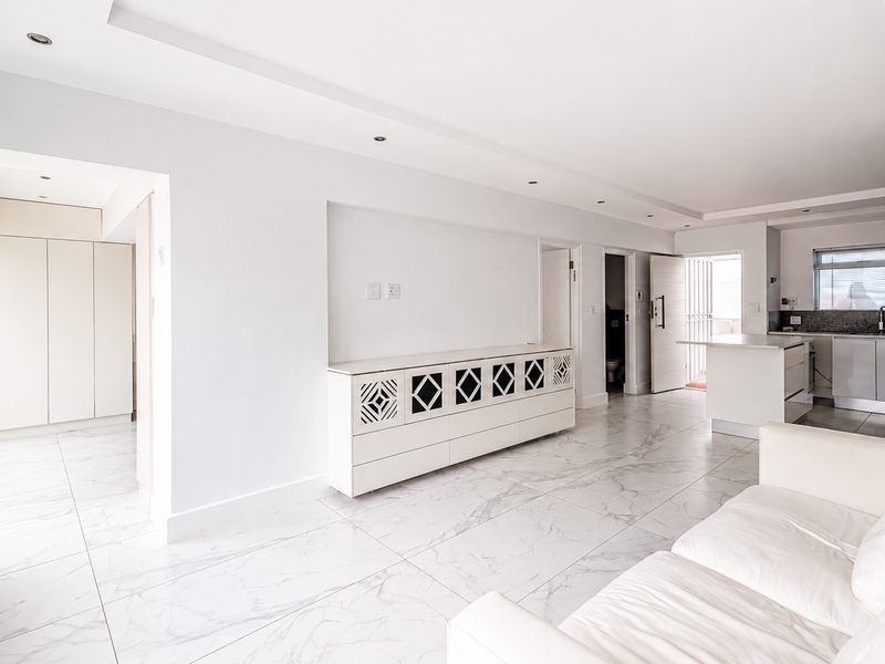 Spacious open-plan living area featuring polished marble-look floor tiles, recessed lighting, and a modern kitchen with integrated cabinetry and a central island.