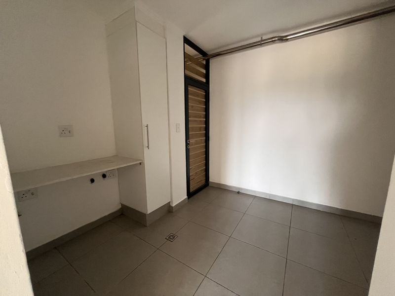 A clean, empty laundry area featuring tiled flooring, built-in cabinetry, and dedicated plumbing and electrical connections for appliances.
