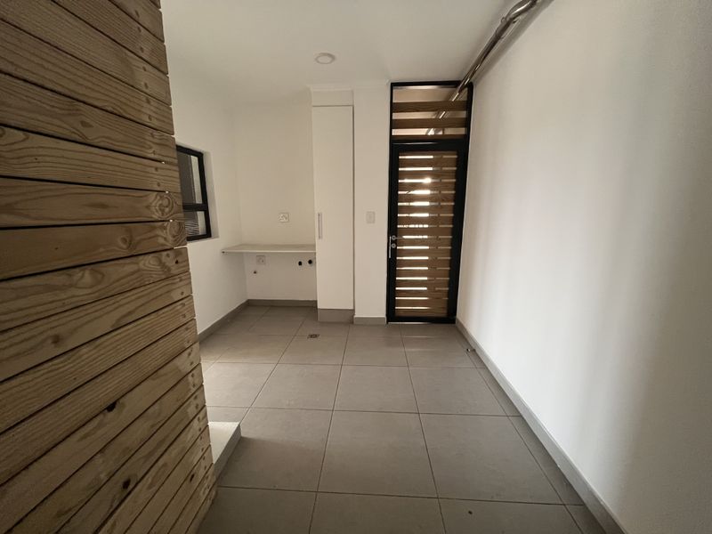 A clean, empty laundry area featuring tiled floors, built-in cabinetry, a functional countertop, and plumbing connections for appliances.