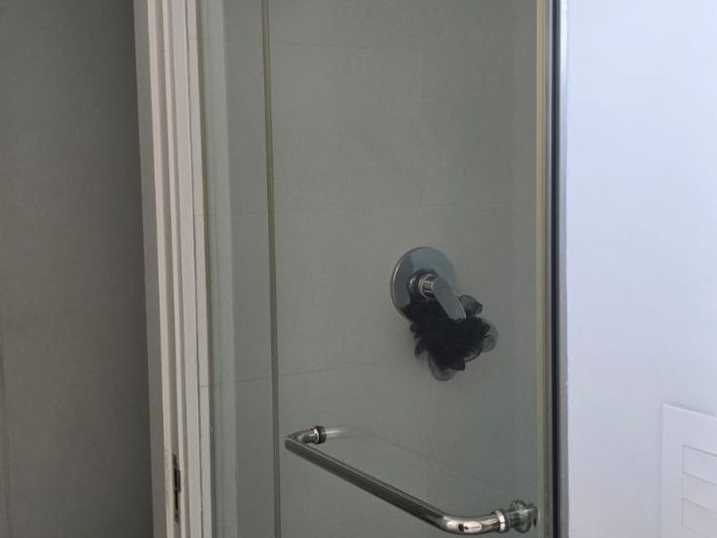 A clean, modern bathroom featuring a glass-enclosed shower with chrome fixtures and a separate toilet area.