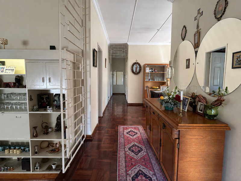 A spacious hallway featuring classic parquet flooring, decorative ceiling molding, and a built-in shelving unit, providing a warm and traditional entrance to the home.
