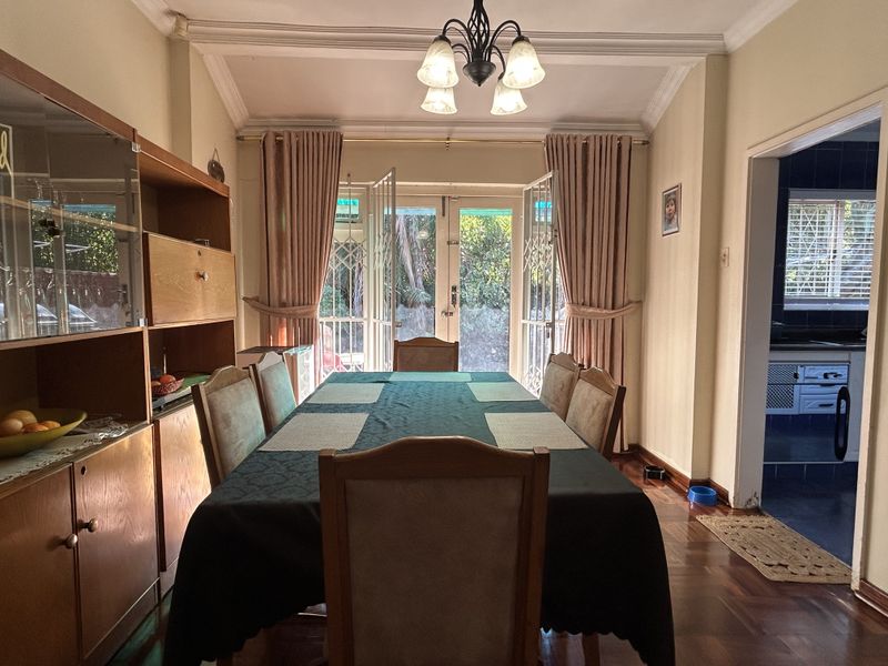 A traditional dining room featuring hardwood flooring, crown molding, and double french doors providing access to the outdoor area.