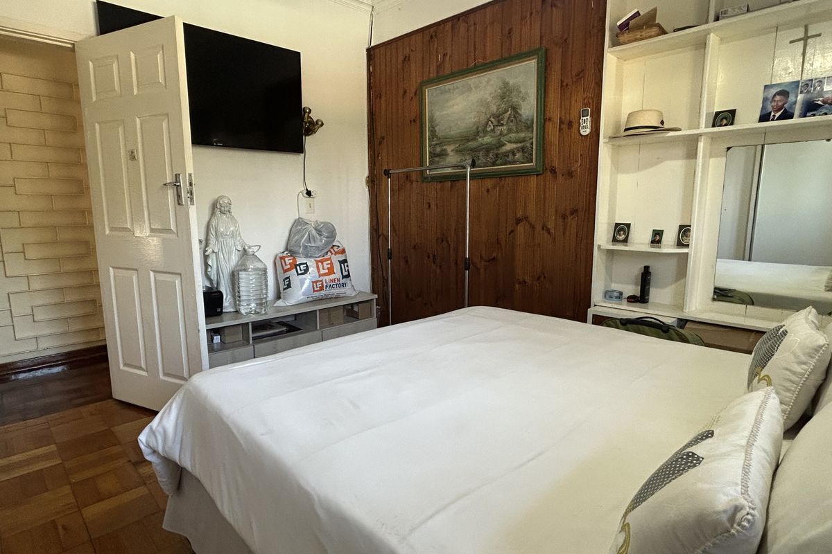 A bedroom featuring parquet flooring, wooden wall paneling, and built-in shelving units.