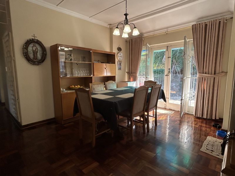 Dining room featuring polished parquet flooring, decorative ceiling molding, and double french doors providing access to the outdoor area.