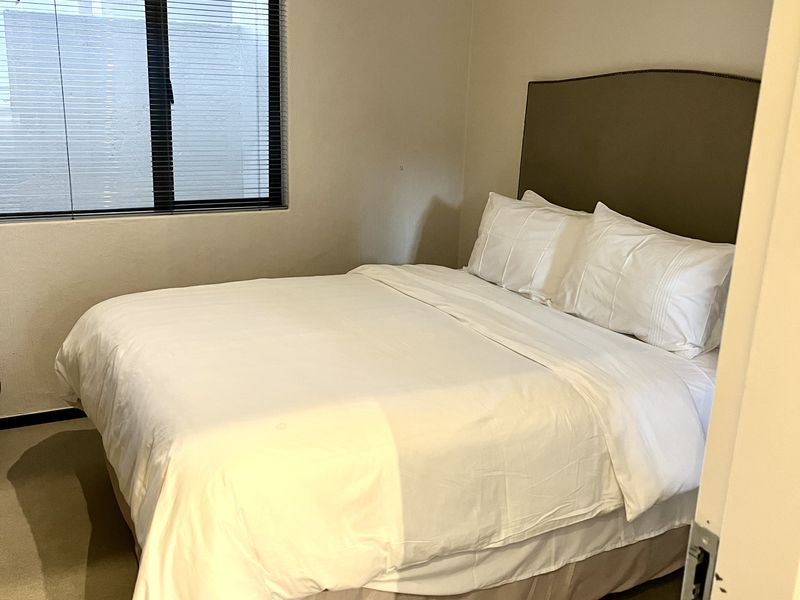 A neutrally decorated bedroom featuring carpeted flooring and window blinds, offering a clean and functional living space.
