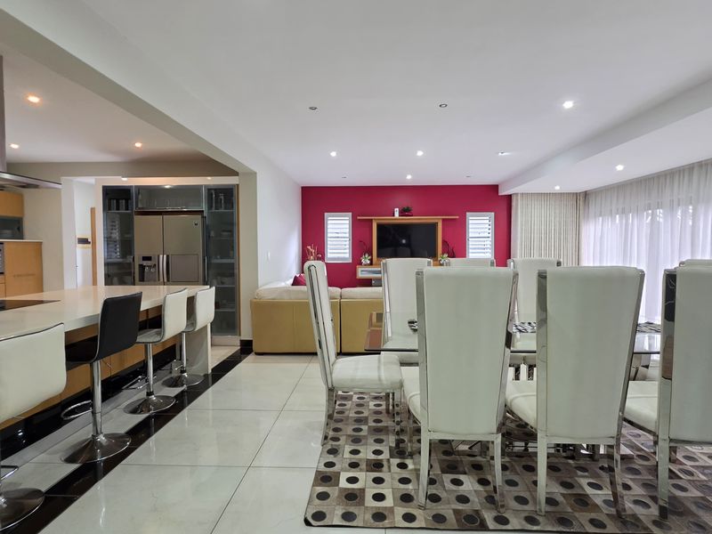 Spacious open-plan living, dining, and kitchen area featuring modern cabinetry, a large island, recessed lighting, and polished tiled flooring throughout.