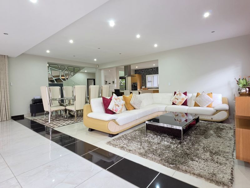 Spacious open-plan living and dining area featuring polished porcelain floor tiles, recessed downlighting, and a seamless flow into the adjacent kitchen space.