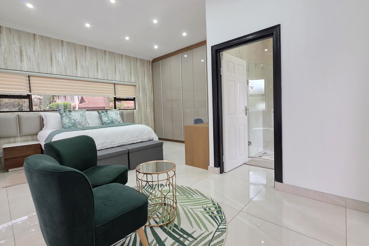 Spacious bedroom featuring modern tiled flooring, recessed downlights, extensive built-in cupboards, and direct access to an en-suite bathroom.