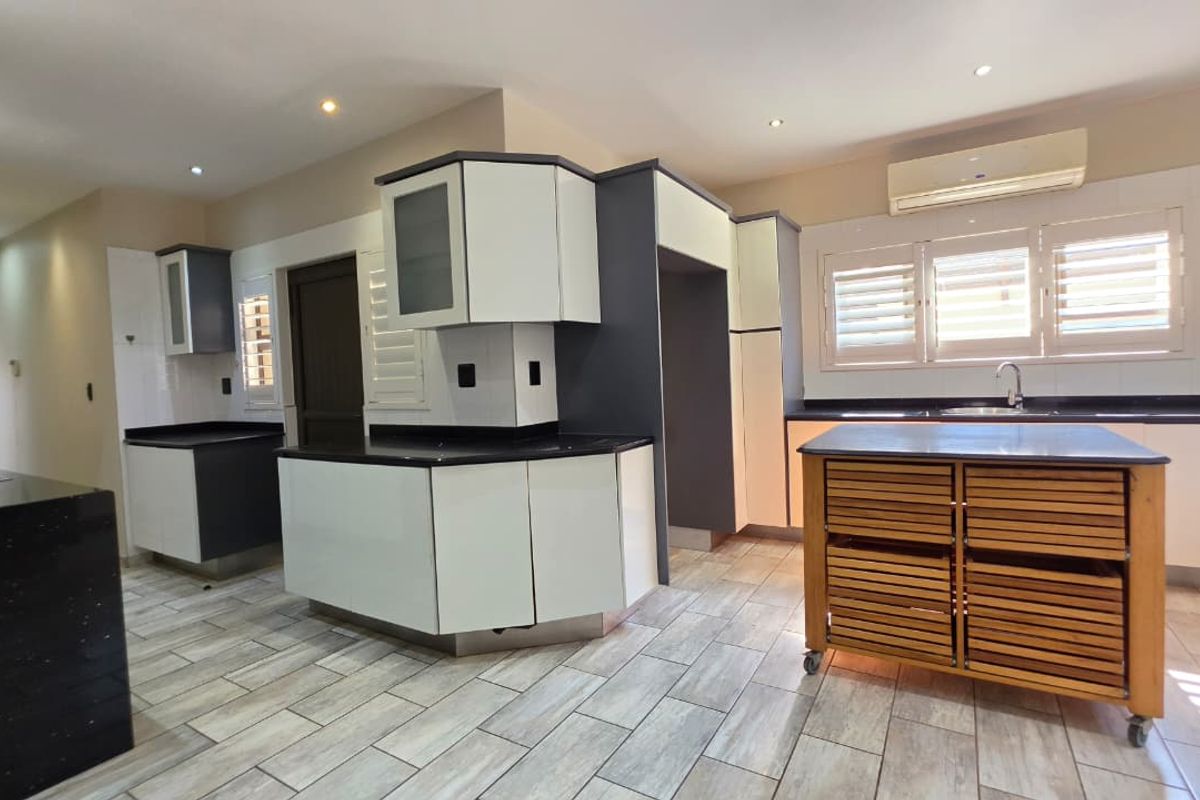 Modern kitchen featuring two-tone cabinetry, dark stone countertops, tiled flooring, and integrated lighting, offering a clean and functional workspace.