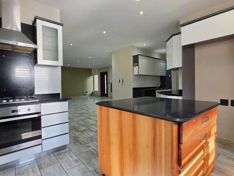 Modern open-plan kitchen featuring a central island, built-in oven, gas hob, and sleek cabinetry, flowing seamlessly into the spacious living area.