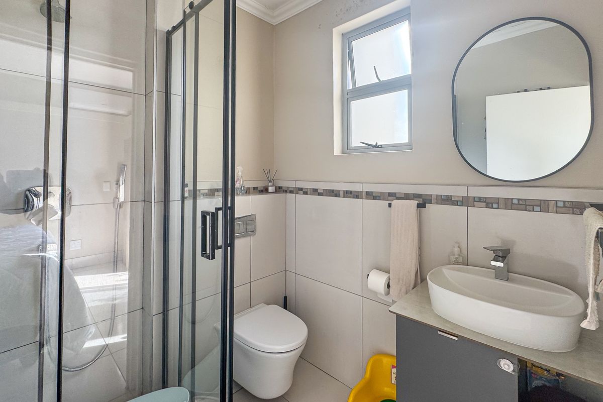 A functional bathroom featuring a glass-enclosed shower, wall-mounted toilet, and a modern vanity with a vessel sink and chrome fixtures.