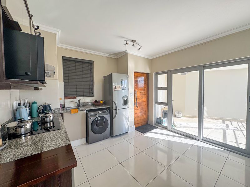 Modern kitchen featuring granite countertops, tiled flooring, and direct access to an outdoor patio area through large sliding glass doors.