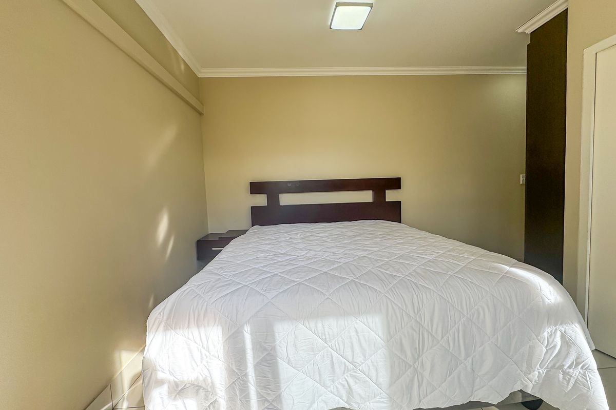 A bedroom featuring tiled flooring, built-in cupboards, and ceiling cornicing, providing a functional and neutral living space.