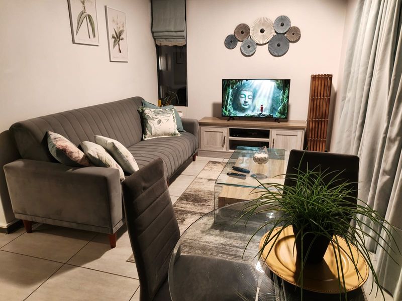 A well-maintained living room featuring neutral tiled flooring and a functional layout, providing a comfortable and inviting space for relaxation.