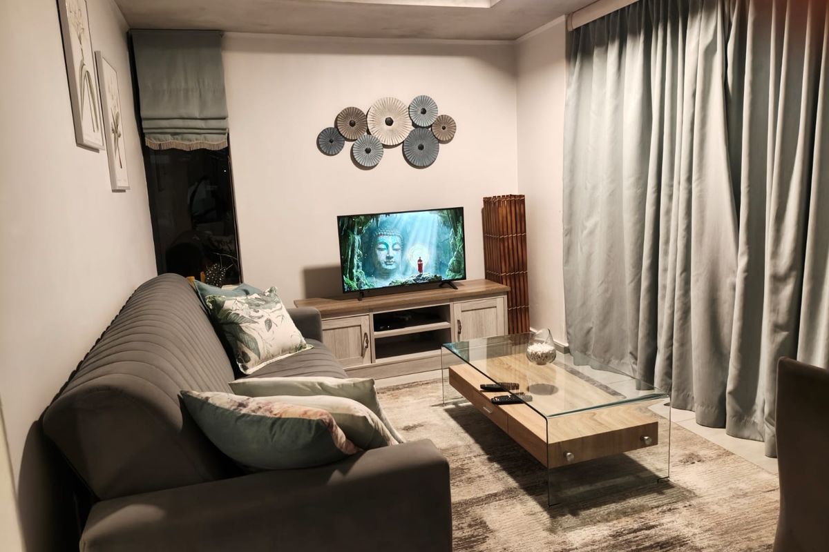 A cozy living room featuring a recessed ceiling with integrated cove lighting and neutral wall finishes.