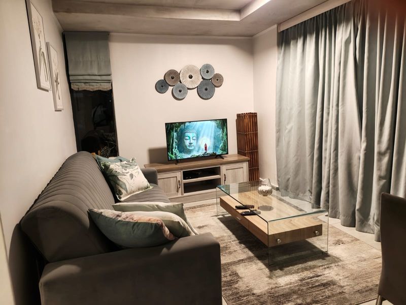 A cozy living room featuring a recessed ceiling with integrated cove lighting and neutral wall finishes.