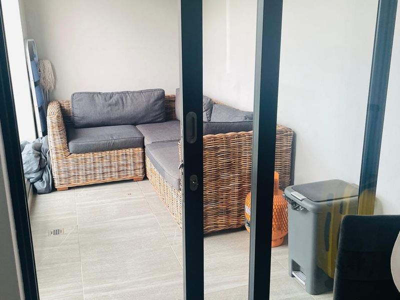A covered balcony area featuring neutral tiled flooring and access via a modern sliding glass door system.