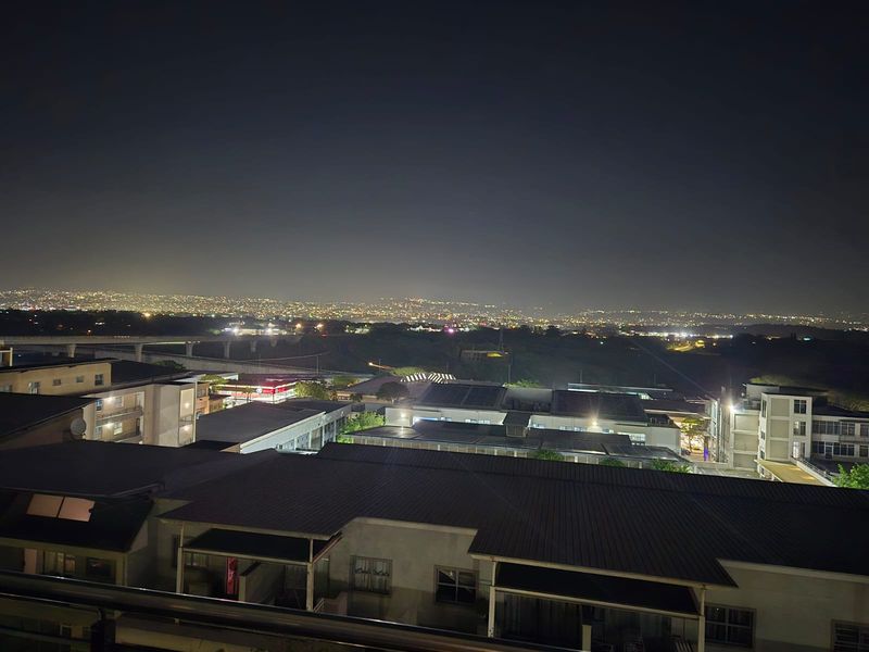 A night-time elevated view overlooking the surrounding residential complex and distant city lights.