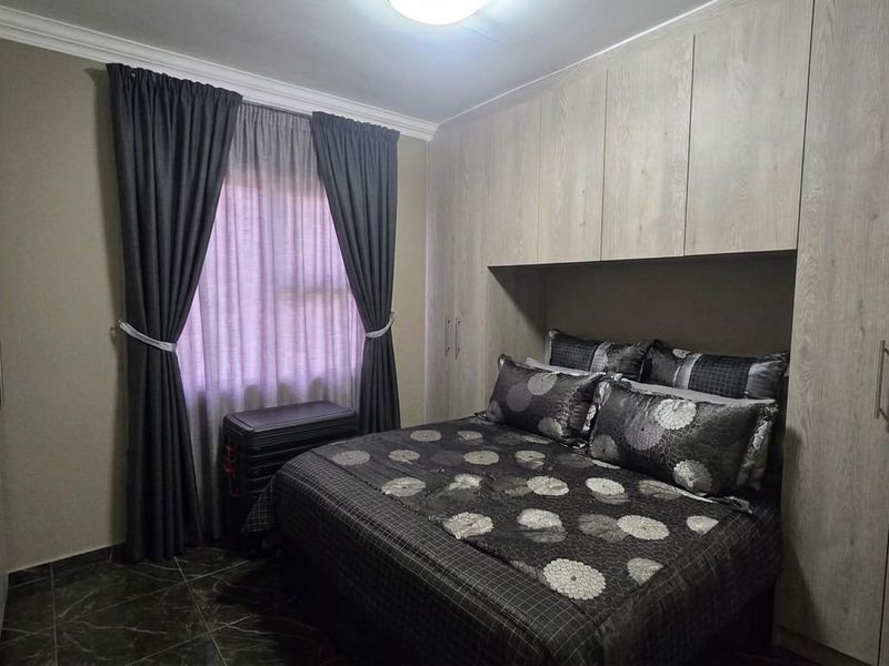 A well-maintained bedroom featuring extensive built-in cupboards, tiled flooring, and decorative cornice detailing.