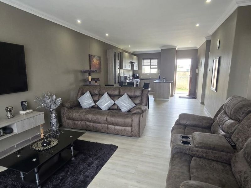 Spacious open-plan living area featuring modern laminate flooring, recessed downlights, and a well-appointed kitchen with a central island.