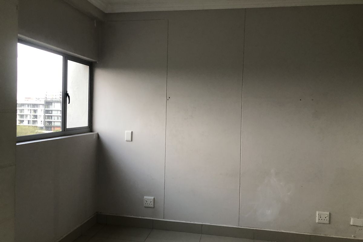 An empty bedroom featuring tiled flooring, aluminium window frames, and neutral wall finishes, ready for personalization.