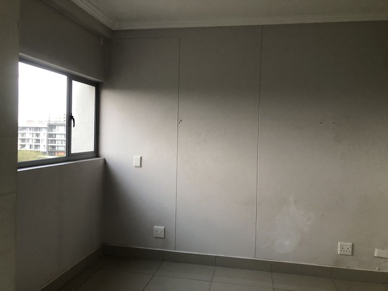 An empty bedroom featuring tiled flooring, aluminium window frames, and neutral wall finishes, ready for personalization.