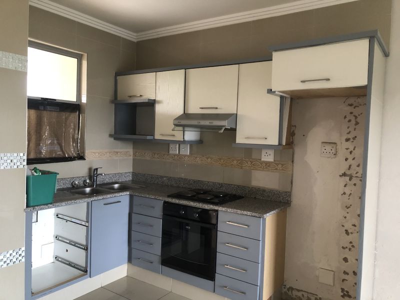 Kitchen featuring granite countertops, built-in oven, and hob. The space requires repairs to cabinetry and wall finishes to restore functionality and aesthetic appeal.