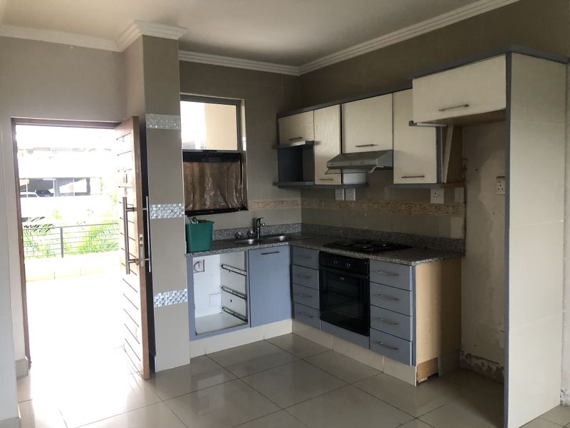 A compact kitchen featuring granite countertops, built-in oven, and hob, currently requiring repairs to cabinetry and finishes.