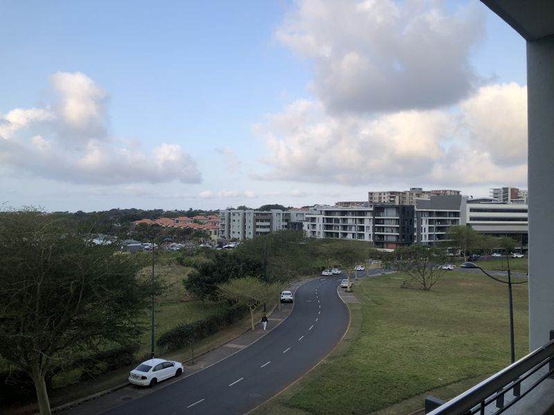 An elevated view overlooking the surrounding neighbourhood, green spaces, and nearby apartment complexes.