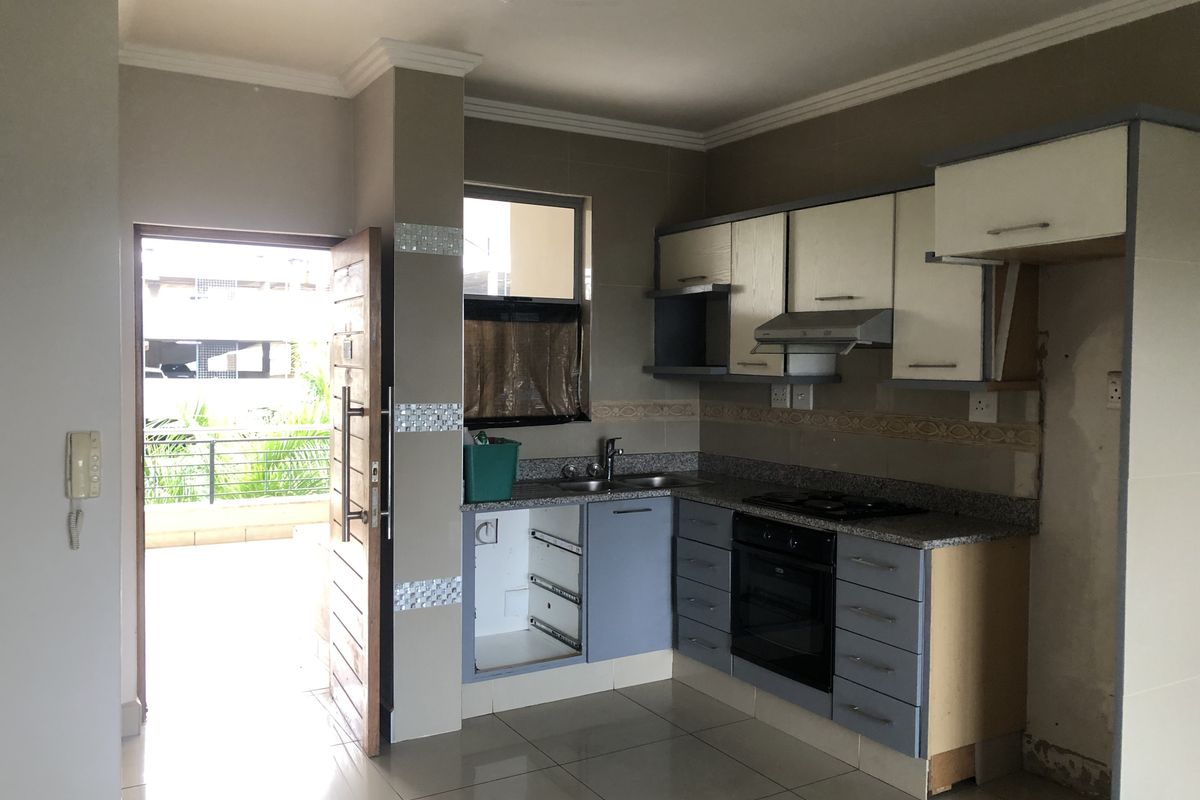 Kitchen area featuring built-in cabinetry, granite countertops, and integrated appliances, with direct access to an outdoor balcony area.