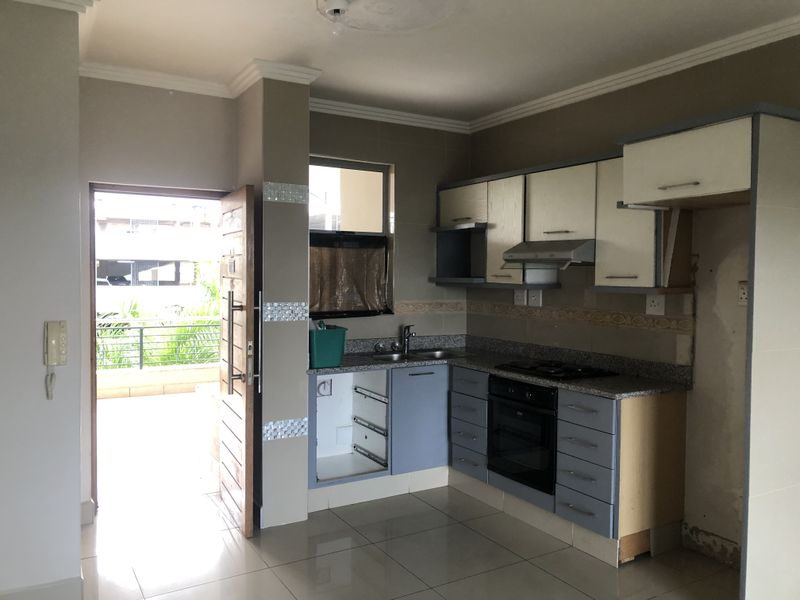 Kitchen area featuring built-in cabinetry, granite countertops, and integrated appliances, with direct access to an outdoor balcony area.