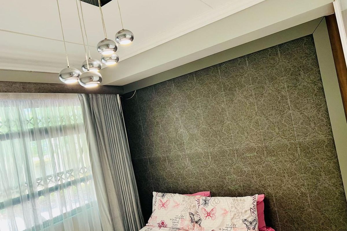 A well-maintained bedroom featuring a decorative feature wall, modern multi-pendant lighting, and a cove ceiling design.