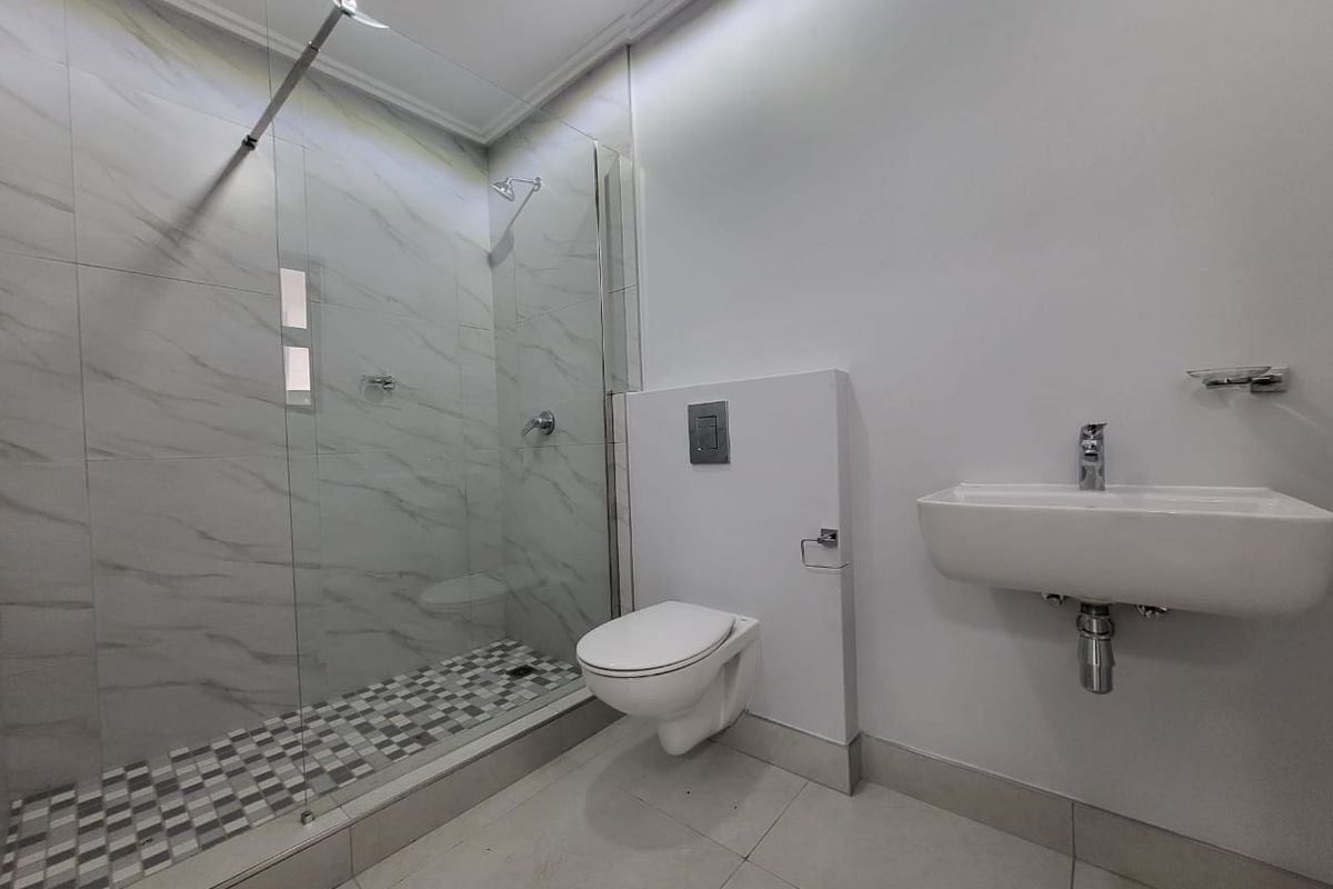 Modern bathroom featuring a walk-in shower with glass screen, wall-mounted toilet, and a sleek wall-mounted basin with contemporary chrome fixtures.