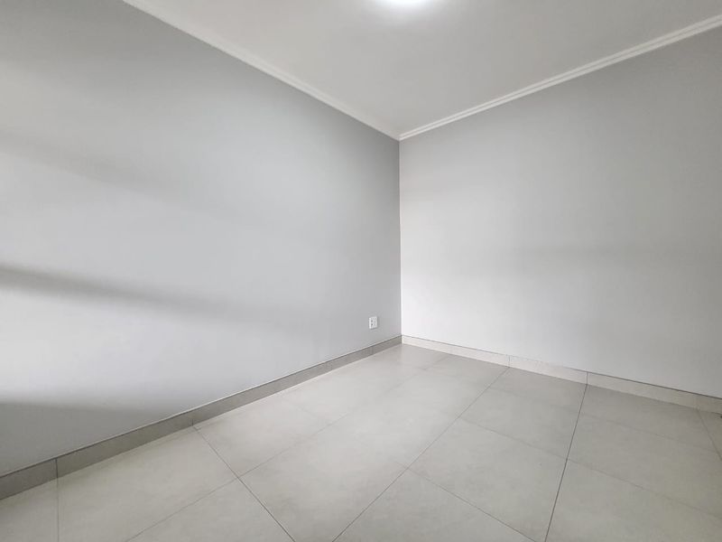 A clean, empty bedroom featuring neutral grey walls, tiled flooring, and simple coving, providing a blank canvas for interior design.