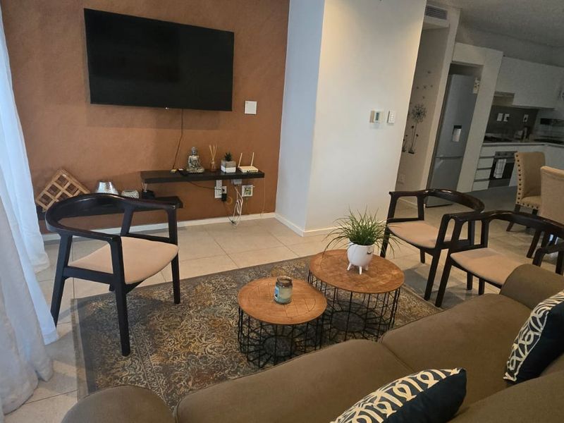 An open-plan living and dining area featuring tiled floors, a modern kitchen with built-in cabinetry, and a neutral color palette.