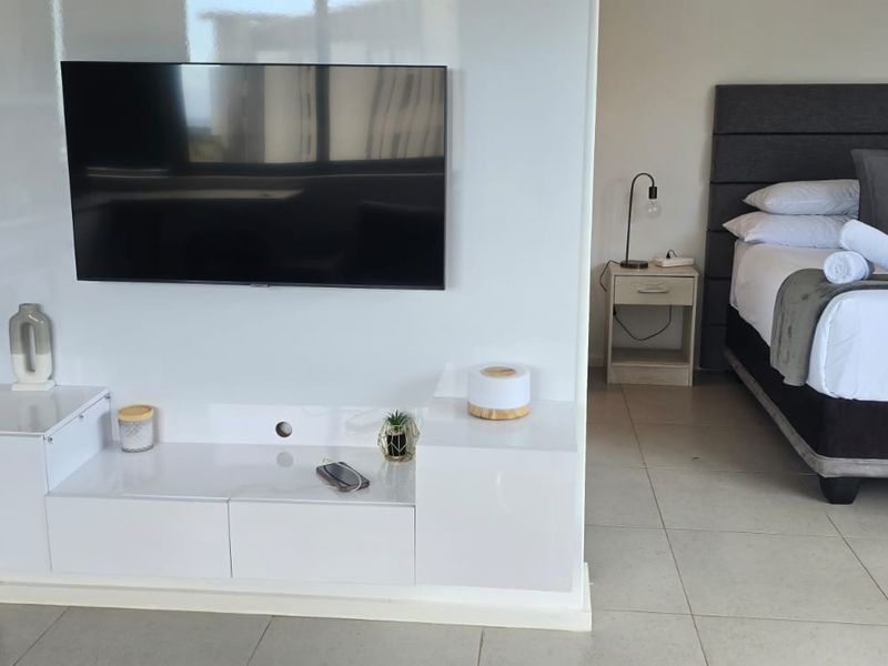 An open-plan studio apartment layout featuring a central partition wall, tiled flooring, and a functional living and sleeping area.